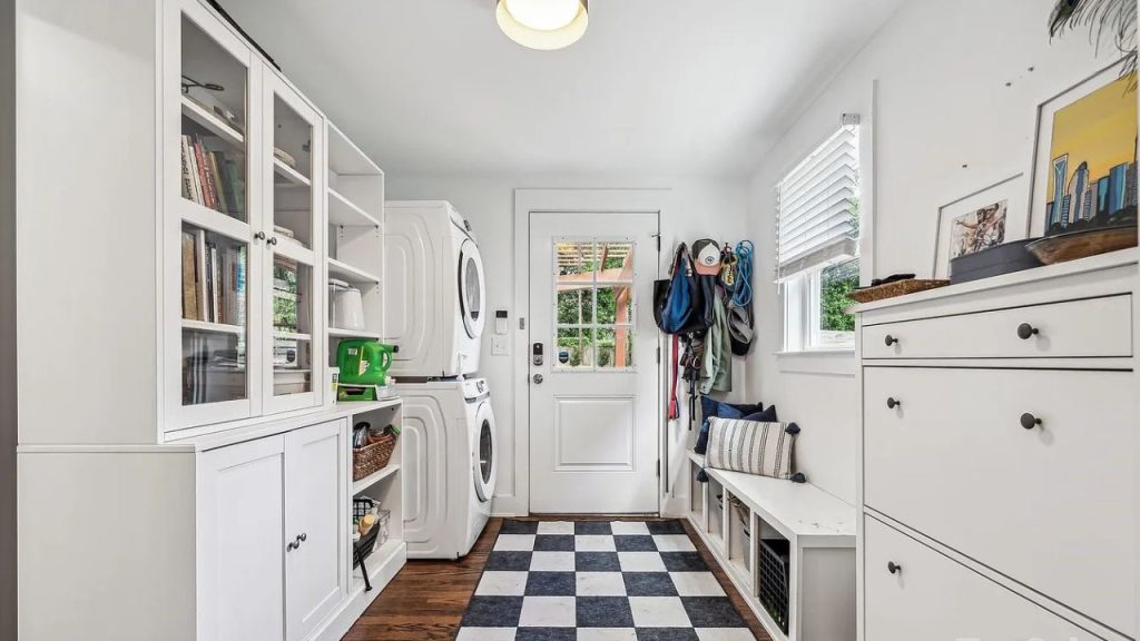 A laundry room with white cabinets, washer-dryer, and a checkered rug.