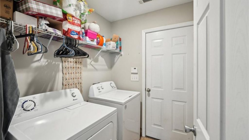 A handy laundry room with white washers, dryers, shelves, and a hanging rod.