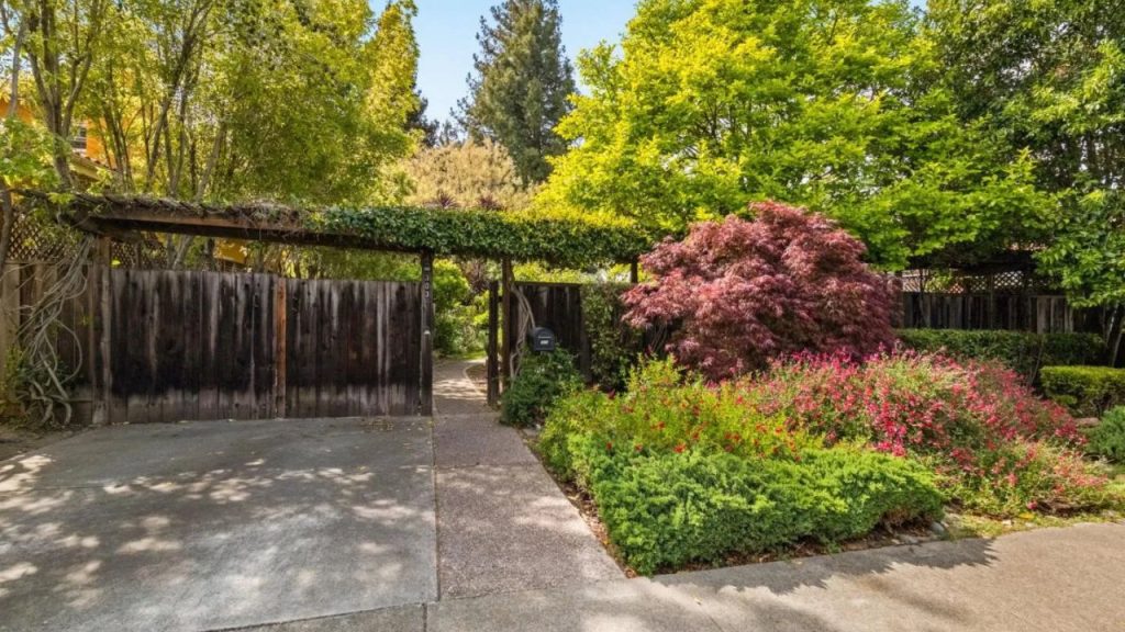 A lush garden entrance with an ivy-covered trellis and colorful flowers.