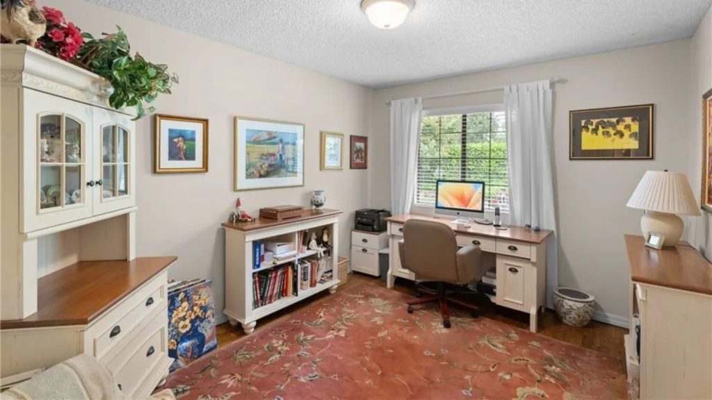 An inviting home office with a desk, computer, wooden cabinets, and vibrant wall art.