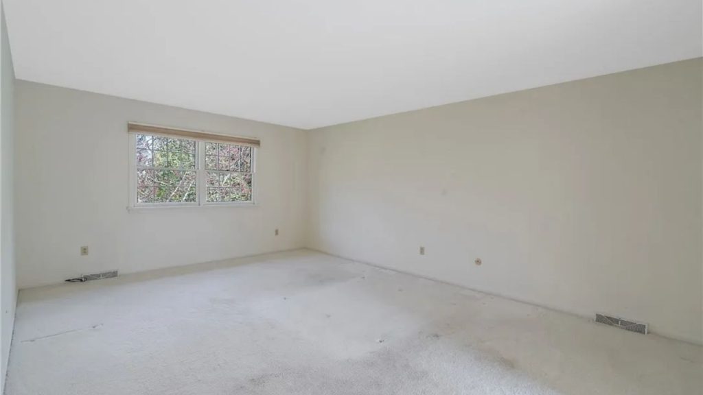 Large primary bedroom with soft carpet and wide window.