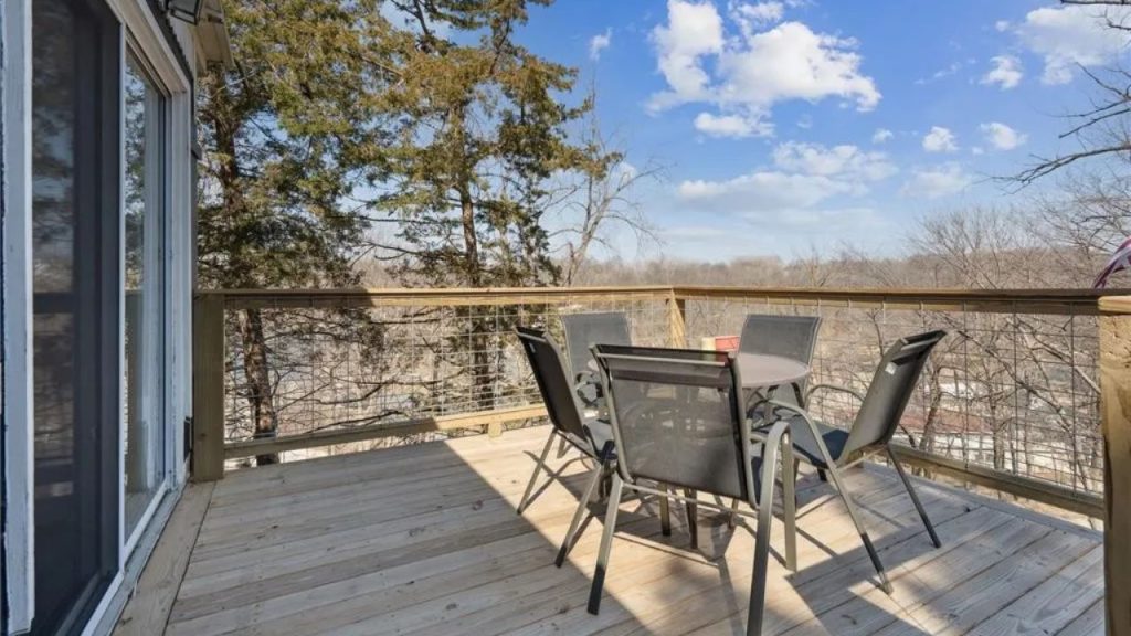 Wooden deck with outdoor seating and a scenic view of trees and hills.