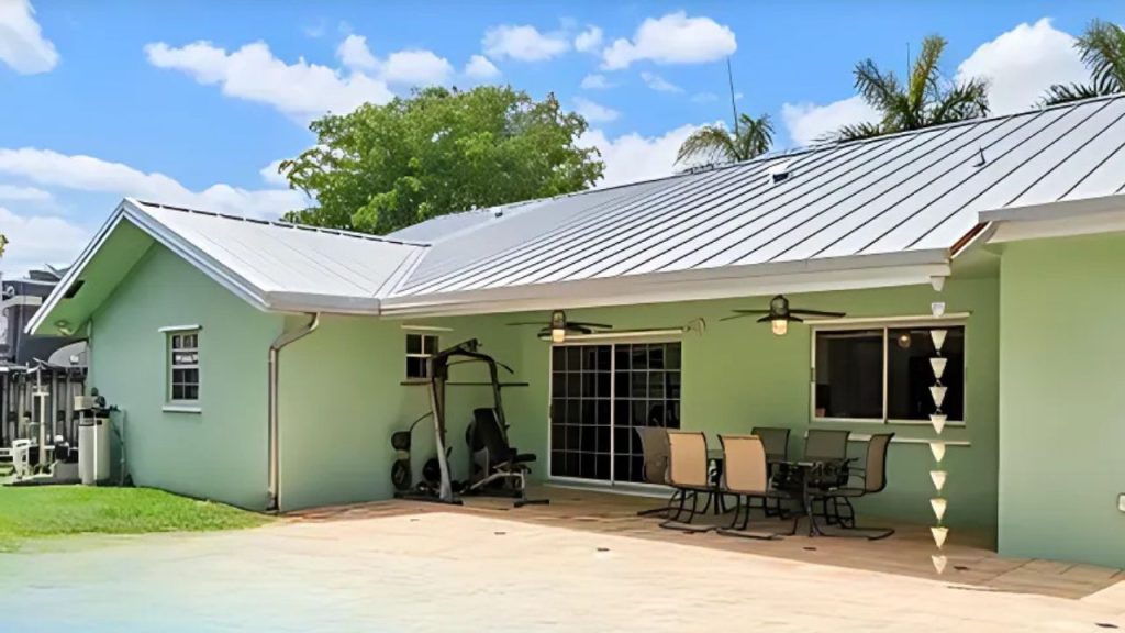 A sunny patio with a dining set, exercise bike, and green house.