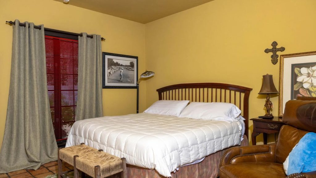 Cozy bedroom with wooden bed frame, warm yellow walls, and rustic decor.