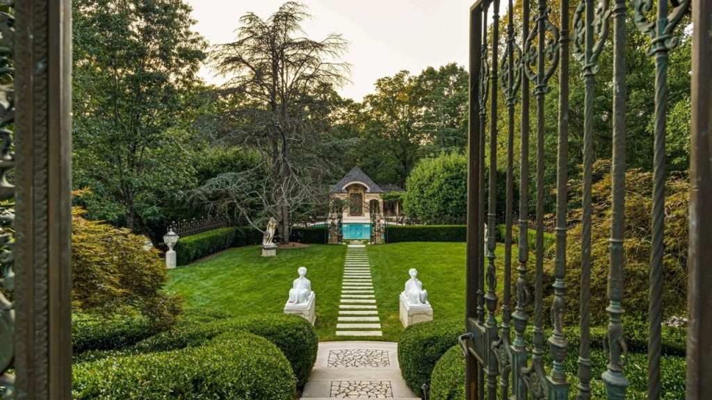 Elegant gated entrance leading to a garden pathway and villa.