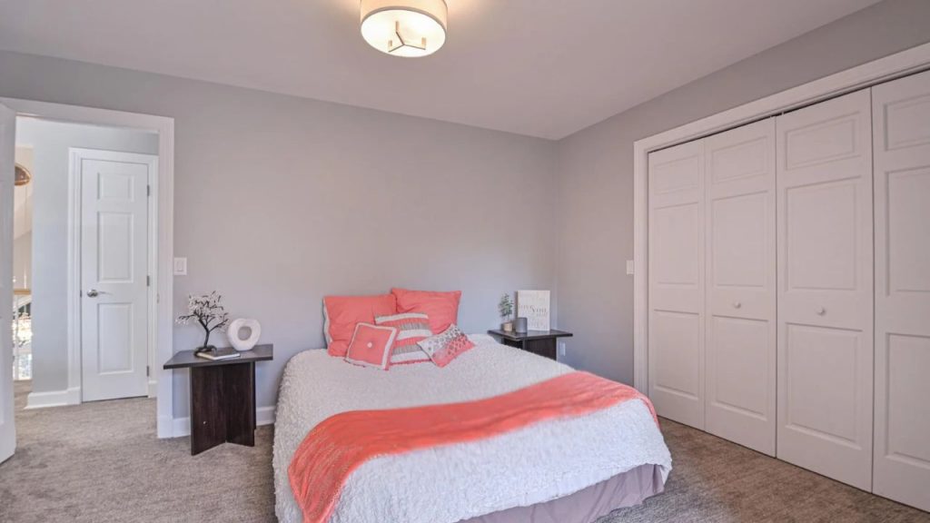 Soft-toned bedroom with coral accents, modern lighting, and a spacious closet.