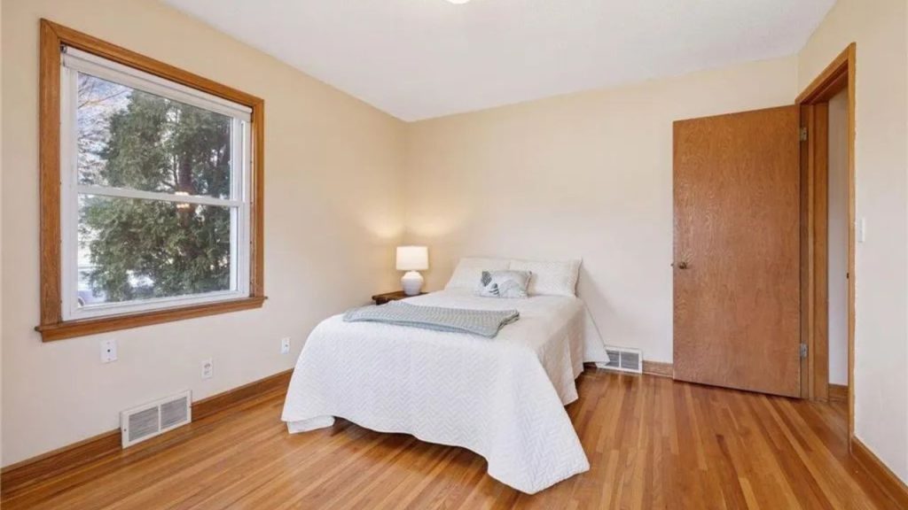 Cozy bedroom with hardwood floors and soft natural light.