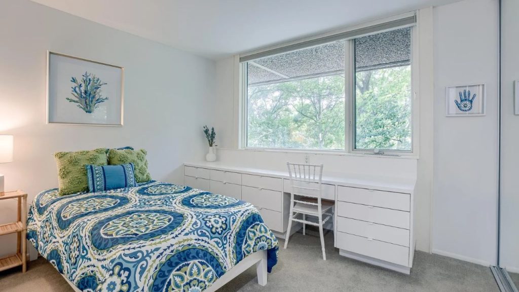 Bright bedroom with leafy window view and blue-green bedding.
