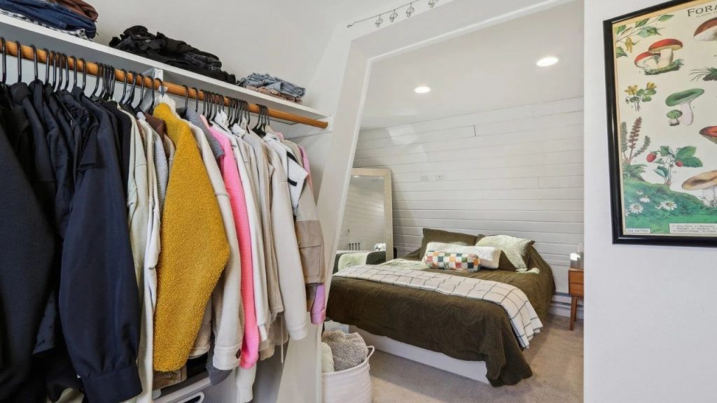 Neatly organized closet opening into a calm bedroom with cozy earth tones.