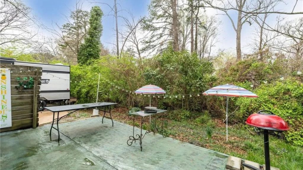 Colorful backyard patio with string lights, umbrellas, and a grill.