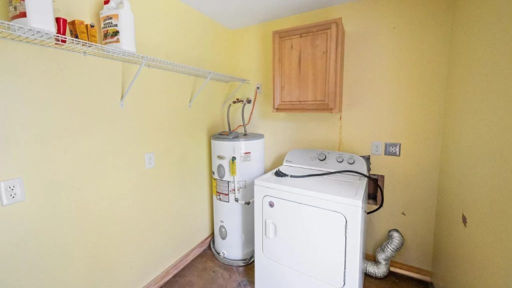 Small laundry room with washer, water heater, and shelf storage.