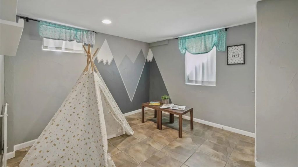 Kids’ playroom with teepee, mountain wall mural, and wooden table.
