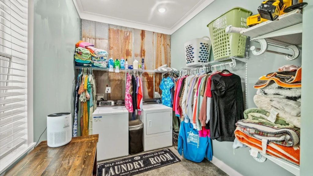 Organized laundry room with a washer, dryer, and rustic metal accent wall.