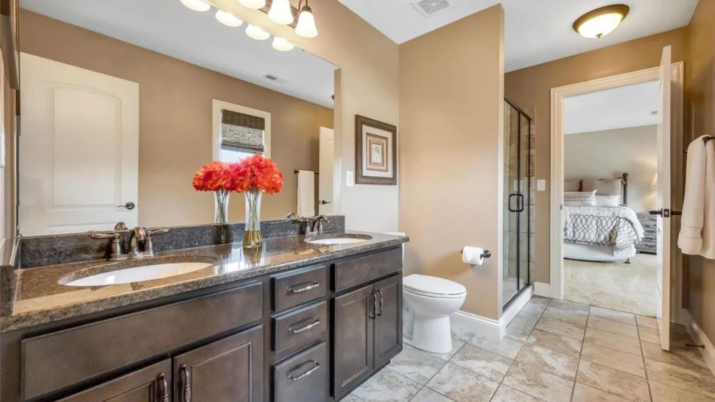 Stylish bathroom with dark wood vanity, granite countertop, glass shower, and connection to a cozy bedroom.