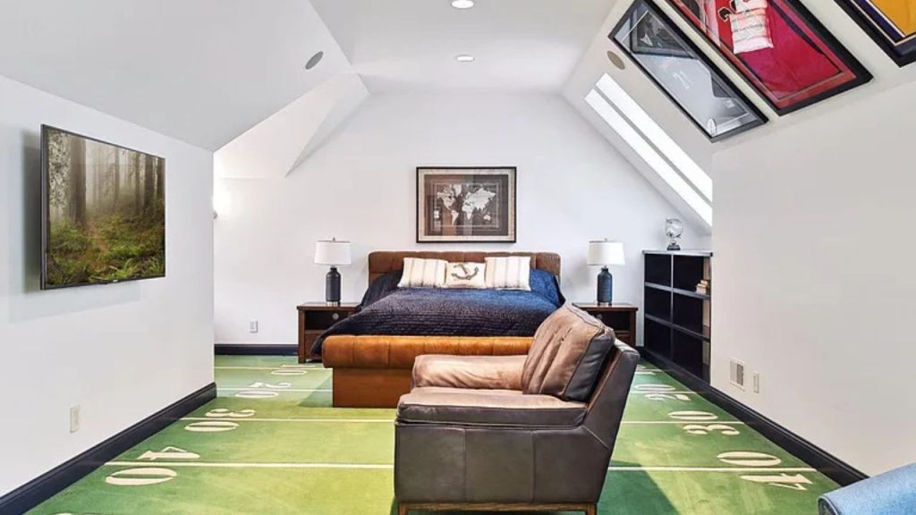 Attic bedroom with football field carpet and sports decor.