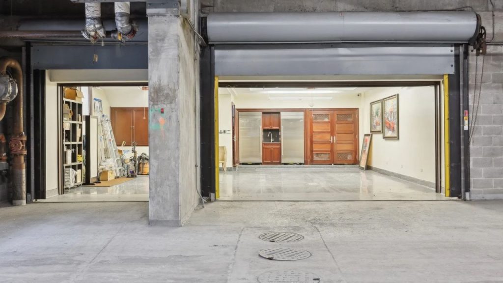 Underground garage with work tools on one side and polished cabinetry and art on the other.