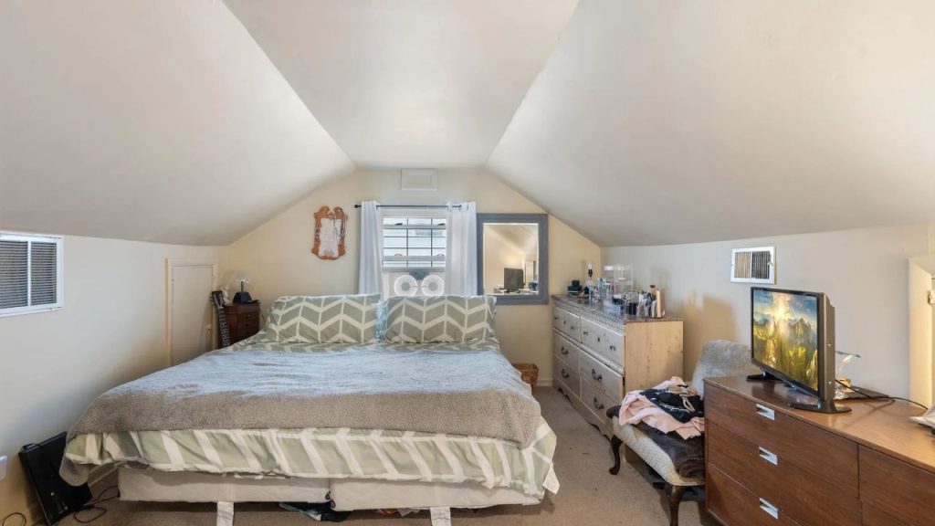 Attic bedroom with sloped ceilings, soft lighting, and cozy decor.
