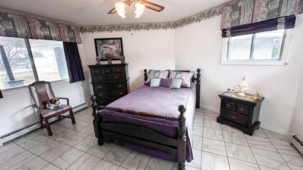 Cozy bedroom with dark wood furniture and purple bedding.