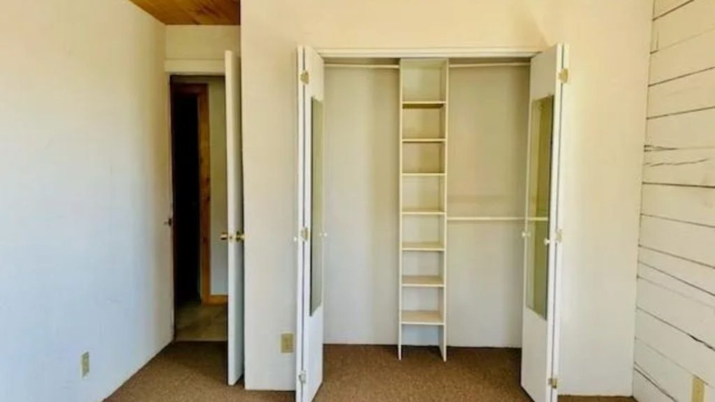 Walk-in closet with shelving, hanging rods, and glass doors.