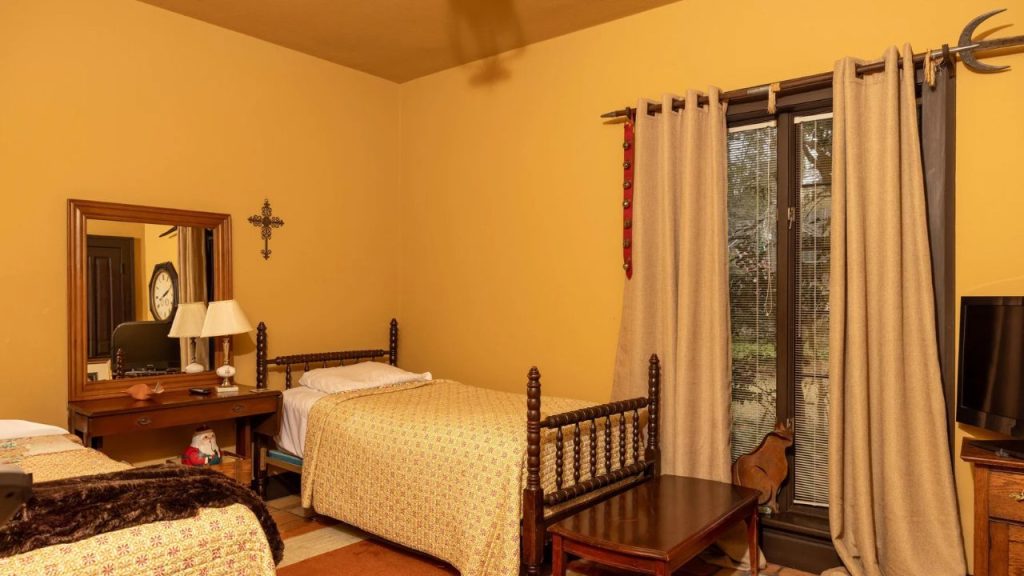 Cozy twin bedroom with vintage wooden beds, warm yellow walls, and rustic decor.