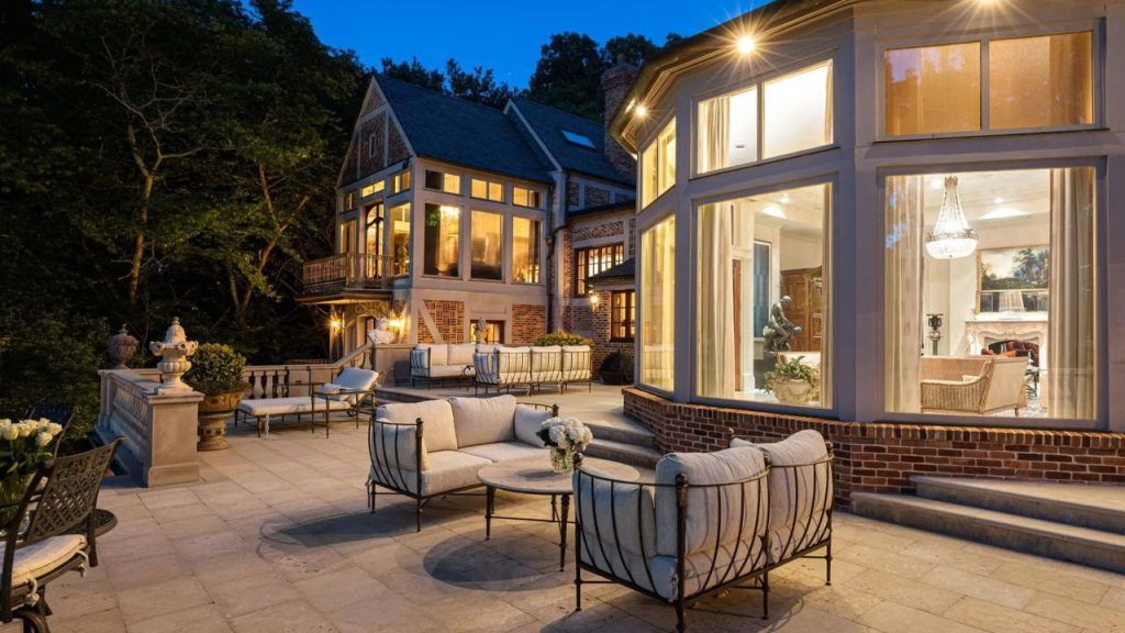 Elegant terrace with plush seating and glowing windows at dusk.