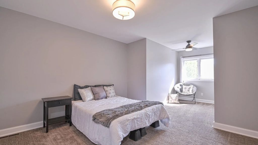 Soft-toned bedroom with lounge nook and natural light.