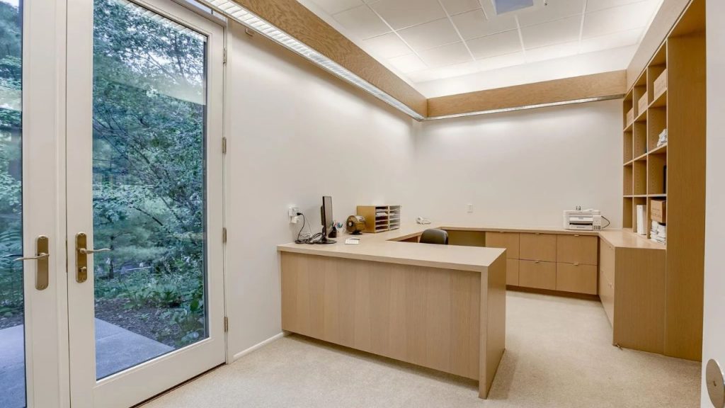 Clean home office with built-in desk and forest view.