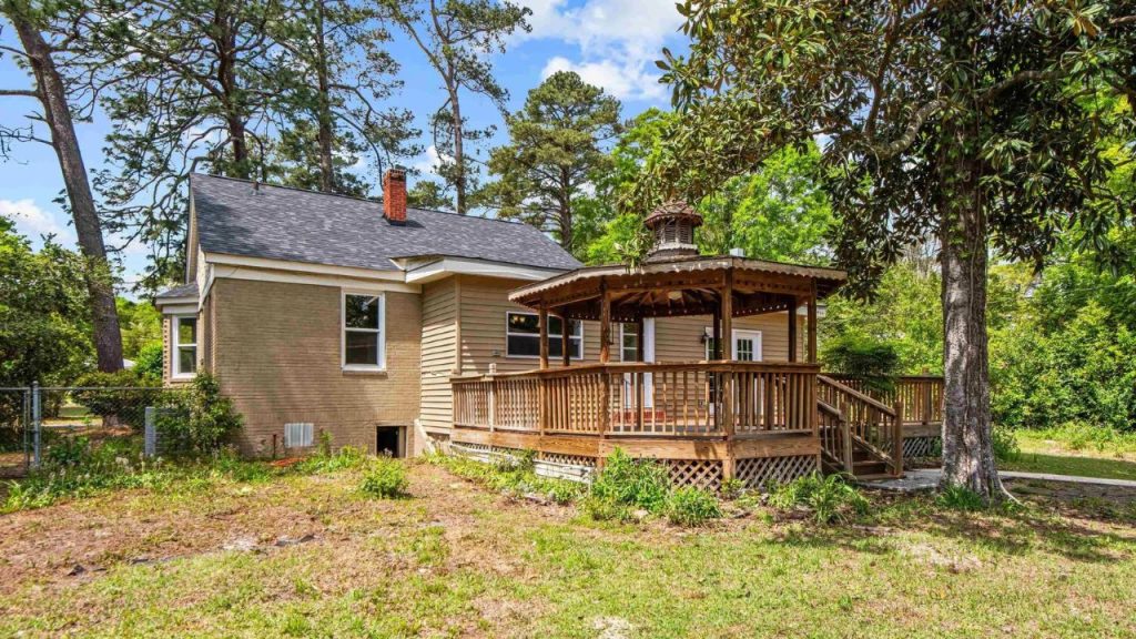 Cozy backyard with a wooden gazebo and deck under tall trees.