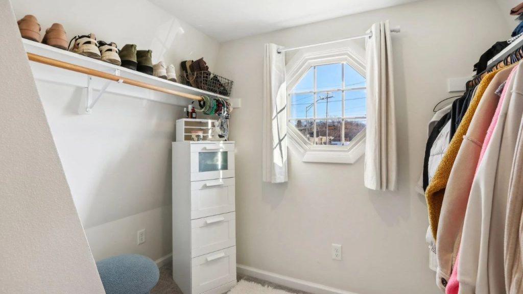Sunlit closet with octagon window, shoe shelf, and hanging coats.