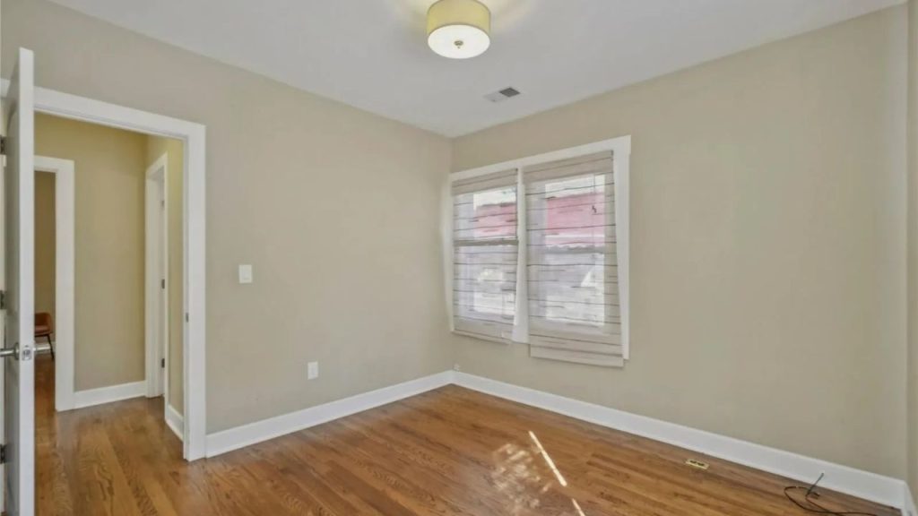 Empty room with hardwood floors and two windows.