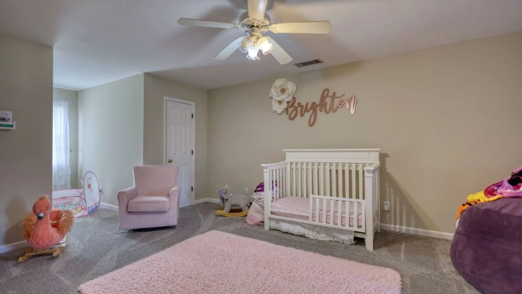 Nursery with white crib, pink glider, name wall art, and soft blush accents.