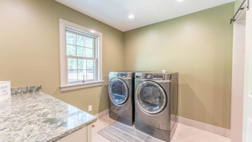 Well-lit laundry room with a modern washer, dryer, and green walls.