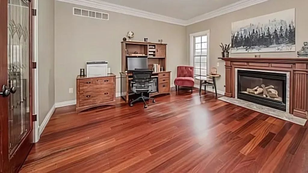 Study with wood desk, fireplace, and red chair by the window.