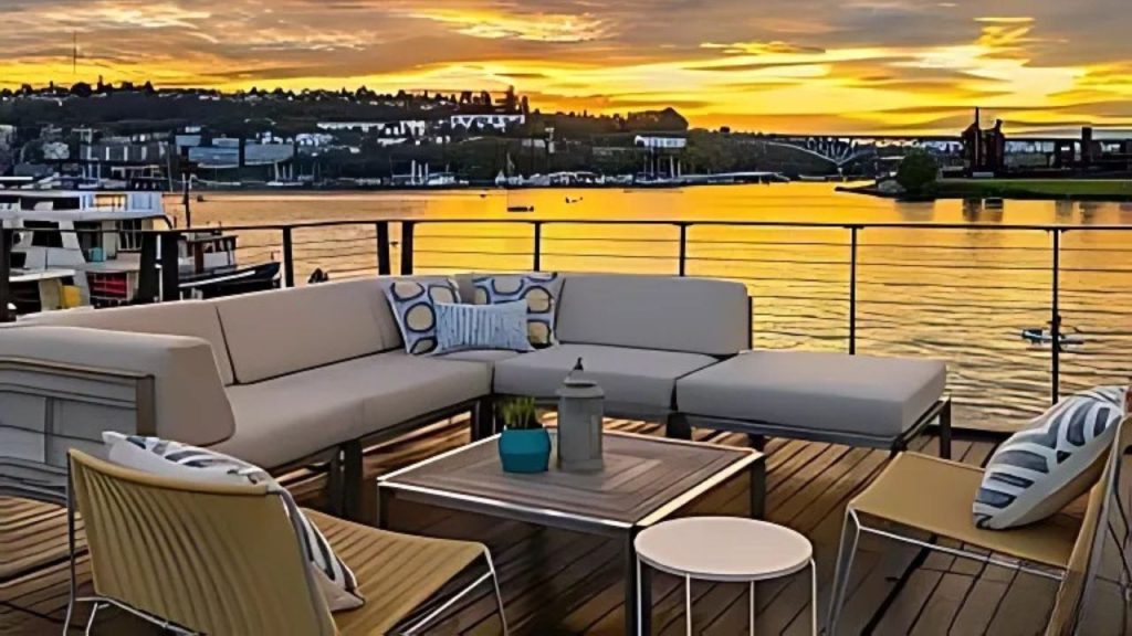 Outdoor seating area on a deck with sunset over the water.