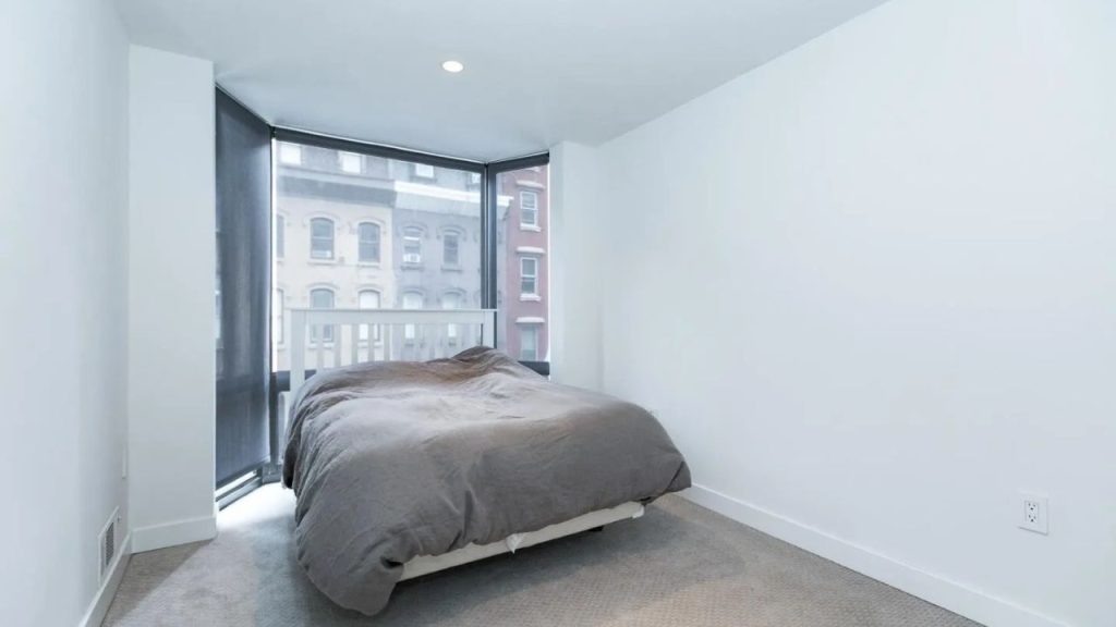 Simple bedroom with large windows and city views.