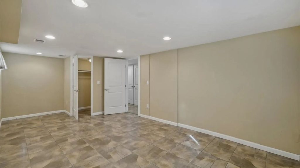Basement room with tile floor, beige walls, and recessed lighting.