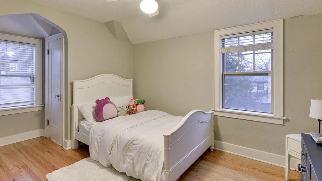 Kids’ bedroom with white twin bed, stuffed animals, and soft green walls.