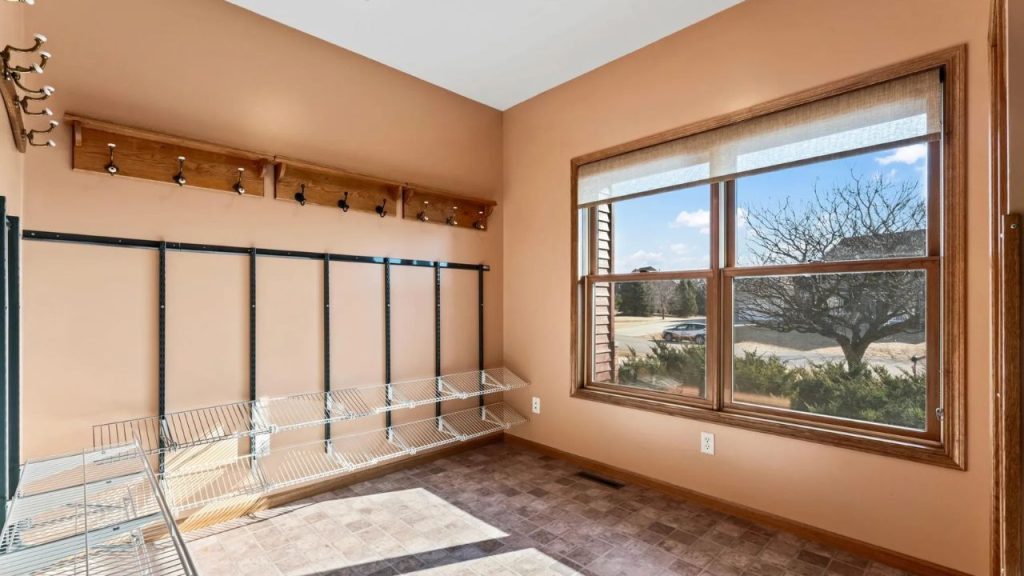 Sunny mudroom with wall hooks and open shelving.