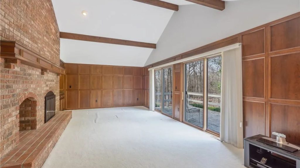 Wood-paneled living room with vaulted ceiling and brick fireplace.