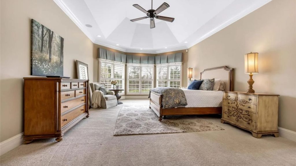 Spacious bedroom with bay windows, elegant furnishings, and a cozy seating area.