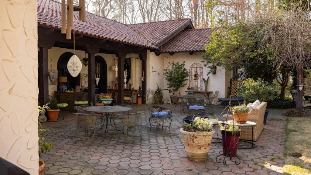 Mediterranean-style courtyard with rustic furniture, potted plants, and a red-tiled roof.