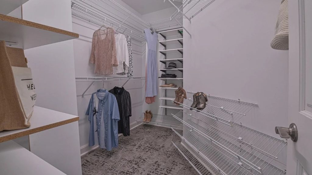 Walk-in closet with hanging clothes, shoe racks, and open shelving.