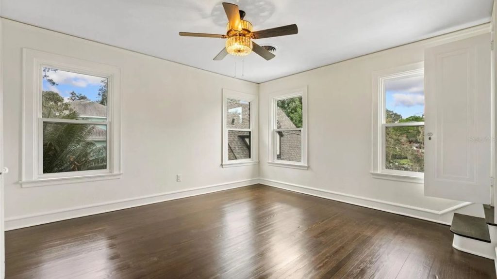 Bright empty room with dark floors and lots of windows.