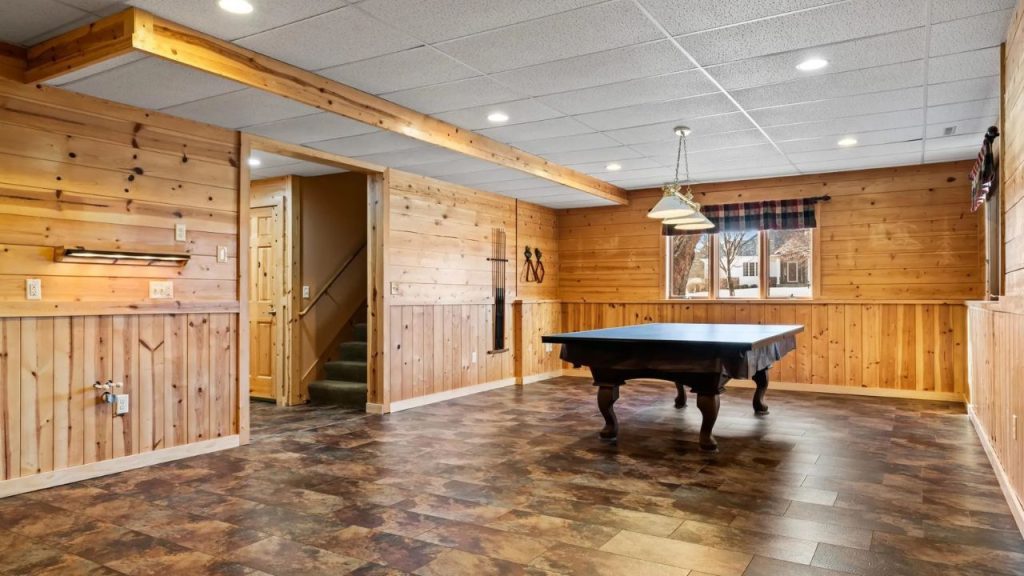 Wood-paneled game room with pool table and window.