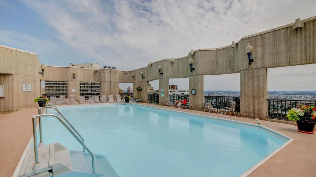 Rooftop pool surrounded by city views and concrete walls.