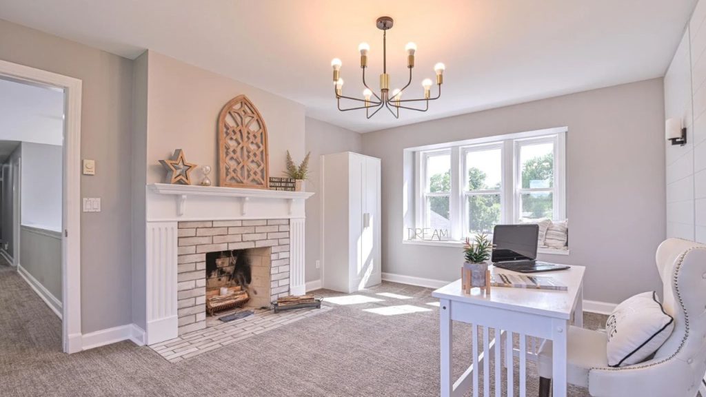 Bright home office with fireplace, desk, and large windows.