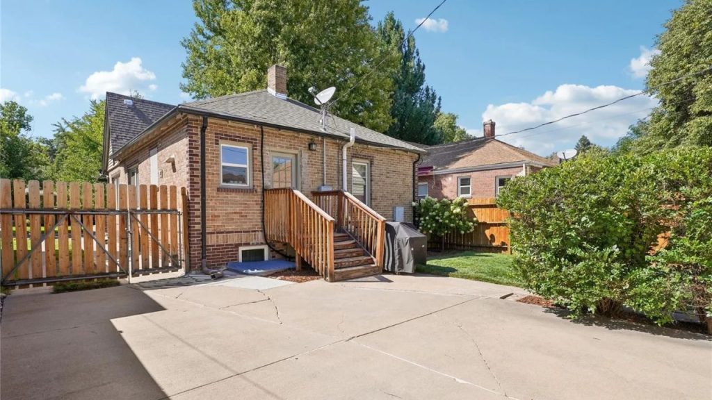 Brick house backyard with wooden steps and concrete drive.