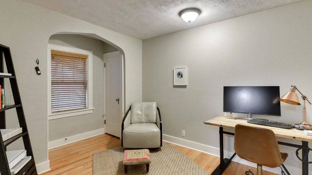 Quiet home office with desk, reading chair, and warm wood floors.