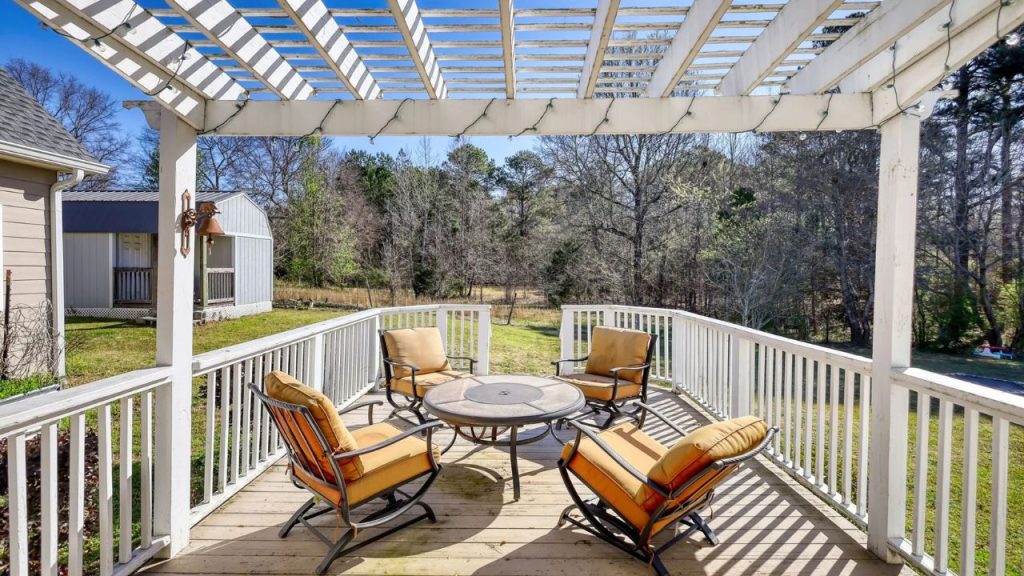 Peaceful back deck with pergola, chairs, and forest view.