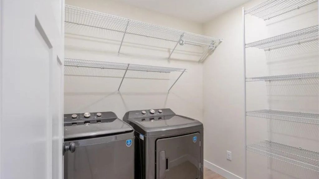 Laundry room with graphite washer and dryer, open shelving, and bright walls.
